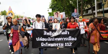 Protesters marching through Ratchadamnoen Road. Two people are holding a banner calling for bail for political prisoners and amnesty for those charged with royal defamation.