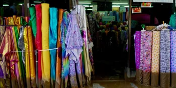 Mud-stained rolls of fabric in front of a shop in Warorot Market.