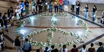 Participants in the gathering on Tuesday night (15 October) standing around a peace sign made of paper containing the name of each person killed during the Tak Bai Massacre. (Photo by Ginger Cat)