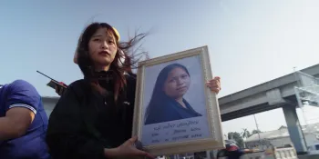 Activist Tantawan Tuatulanon, holding a photo of Netiporn, on her way to the Thanyaburi Provincial Court