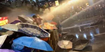 Water cannon blasts into protesters who shield themselves with umbrellas on 16 October 2020