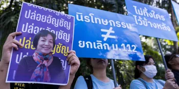 A participant in a gathering in front of the the Central Women Correctional Institution on 22 November 2024 holding Anchan's picture. The blue banner held by the second participant says "Amnesty ≠ repeal royal defamation law." (File photo)