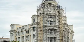The exterior of the Deves Insurance Public Company Limited building is visible, but a zinc fence is still in place and workers are still working around the building.