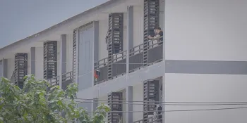 Men smoke cigarettes outside one of KK Park 1’s locked and guarded compounds in Myawaddy, Karen State. Bodies have been discovered just meters from this location (Saw Daniel / Myanmar Now)