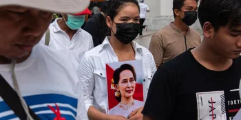 A participant in a Labour Day protest organised by a network of migrant workers from Myanmar holding a picture of Aung San Suu Kyi (Photo by Peerapon Boonyakiat)